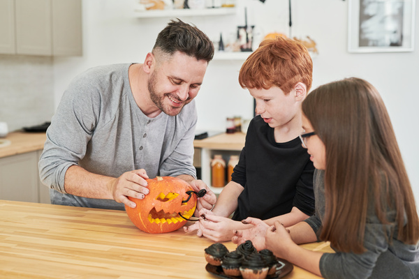 Man with His Children Decorates Pumpkin for Halloween